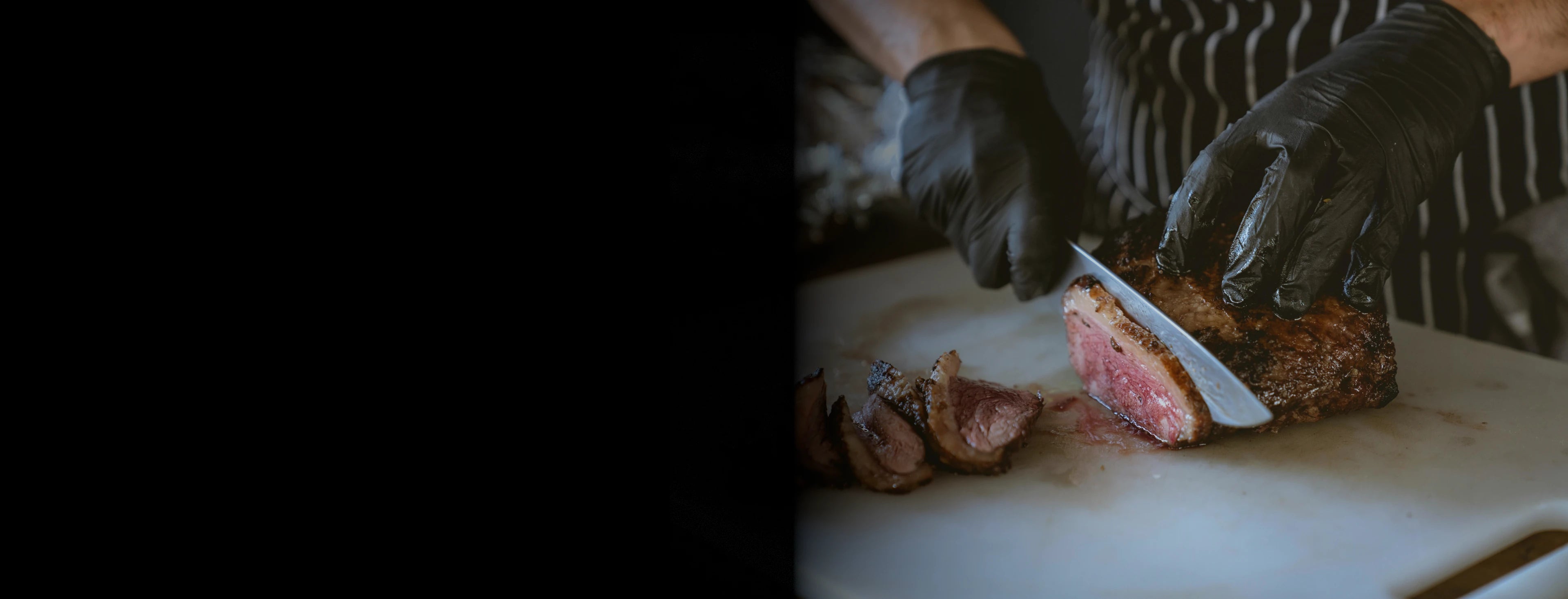 Chef Cutting Steak with a Damascus Steel knife on a white  cutting board with black gloves on. | Boulder & Blade